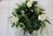 Dekorativer grüner Kranz mit weißen Rosen (Kunstblumen) und weißen Bändern